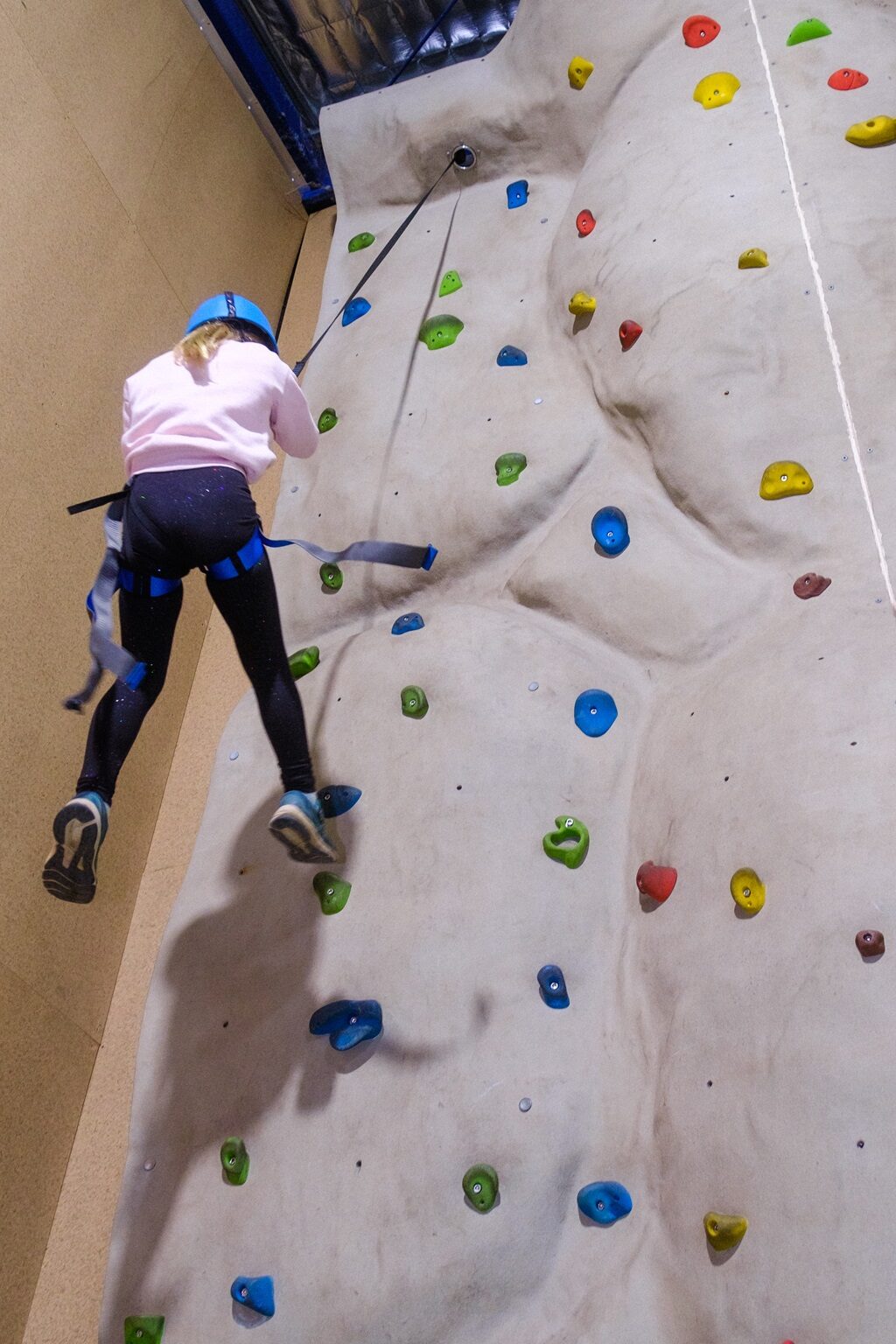 A camper on the rock climbing wall at Oasis Camp